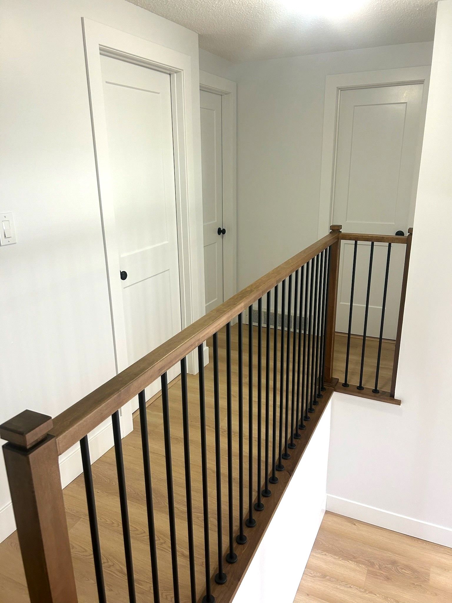A hallway with a wooden railing and a metal railing built by Ironside Construction