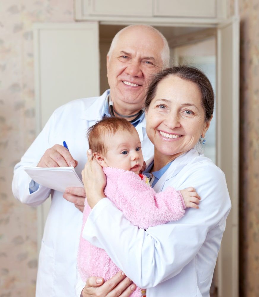 A woman is holding a baby while a man writes on a clipboard.