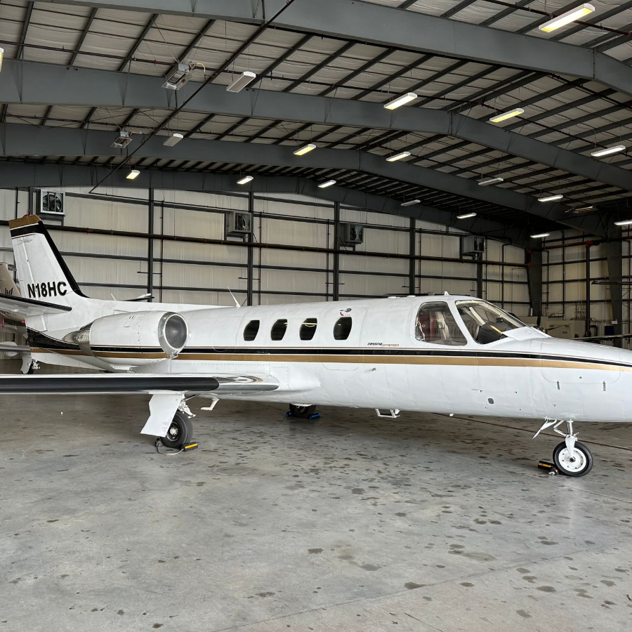 Small white private jet parked inside a hangar