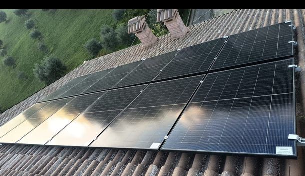 Pannelli solari installati su un tetto inclinato adiacente a un prato.
