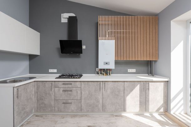 Cucina moderna e minimalista con mobili grigi, ripiani bianchi, parete rivestita in listelli di legno e luce naturale proveniente da una finestra.
