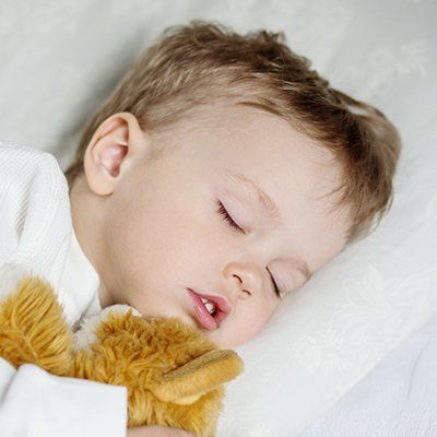 A baby is sleeping with a stuffed animal in his arms