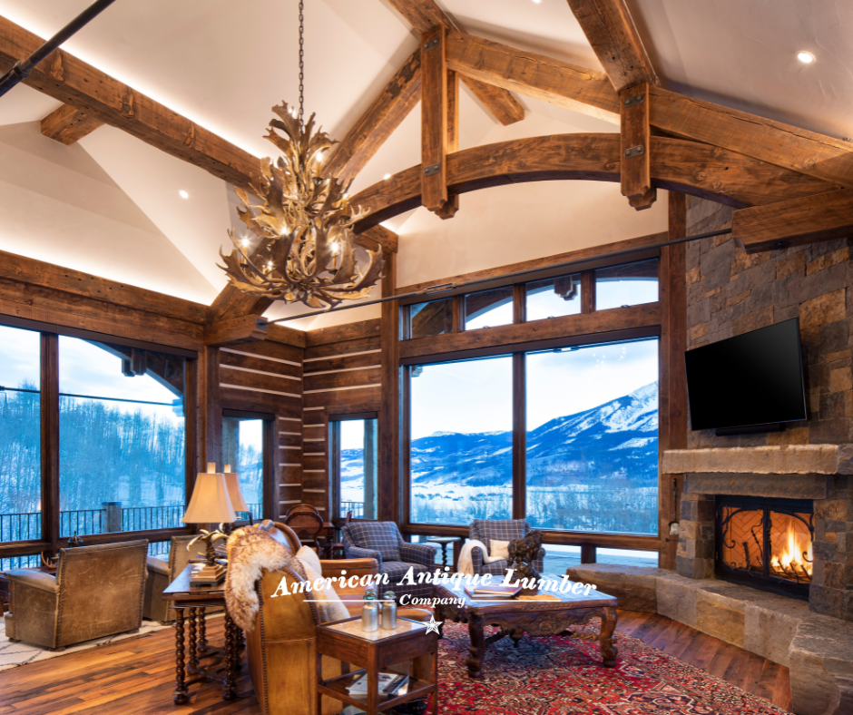 Reclaimed decorative wood trusses, moose antler chandelier,  stone fireplace with fire, and Colorado mountains seen through the windows and dusk.