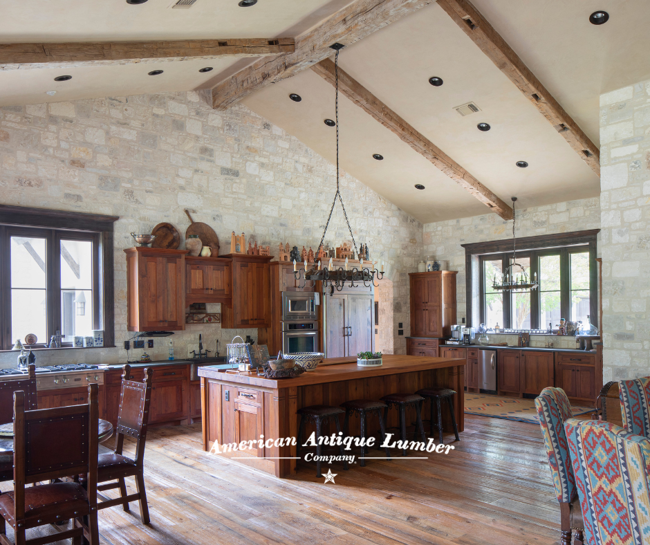 Wooden kitchen island with wood floors, stone walls, white wall vaulted ceiling with reclaimed hand hewn beams. 