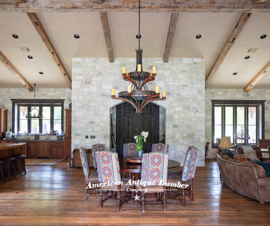 Round wood dining table surrounded by south west upholstered chairs facing stone wall entryway with wooden door and large circular wooden chandelier.