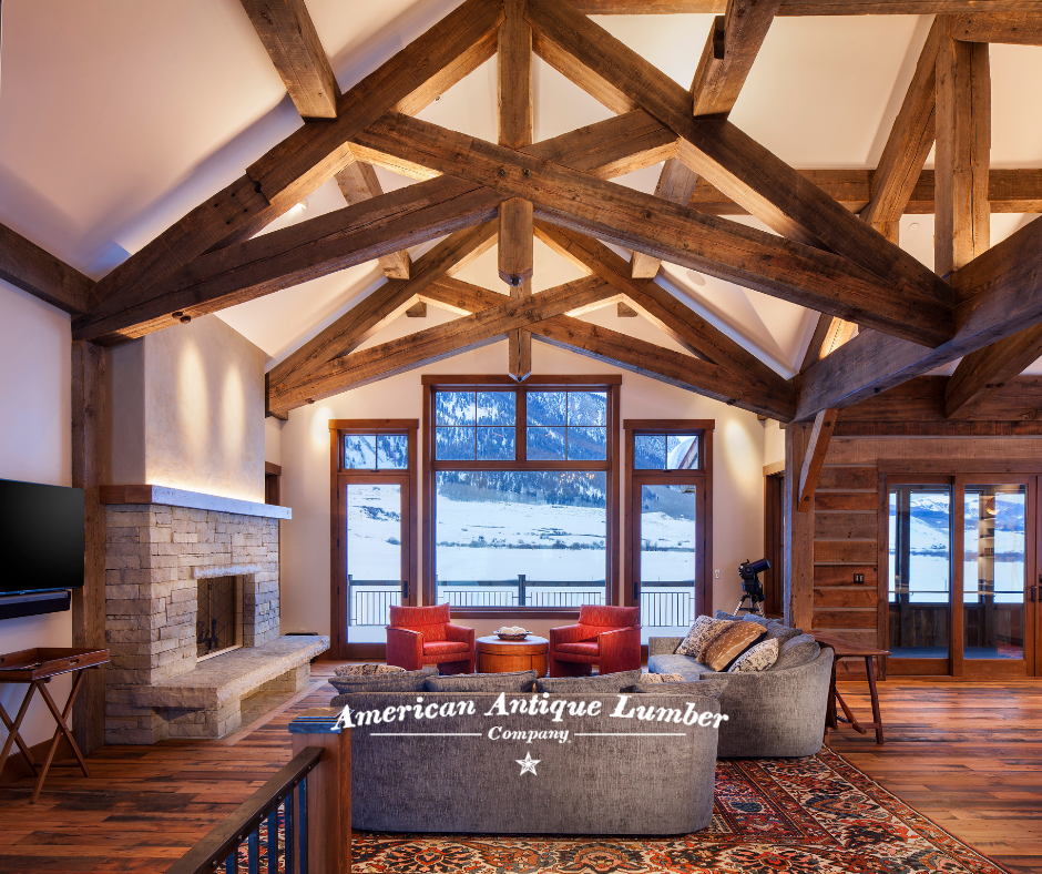 Reclaimed scissor trusses back lit, stone fireplace on the left with snowy Colorado mountains showing through the windows