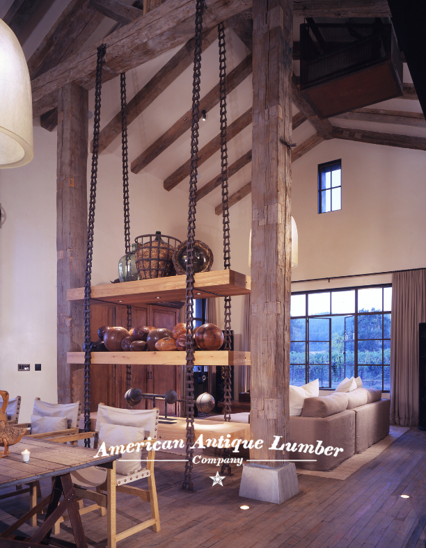 Industrial style living room has shelves hung with metal chains flanked by reclaimed hand hewn timbers and a vaulted ceiling with reclaimed beams. 