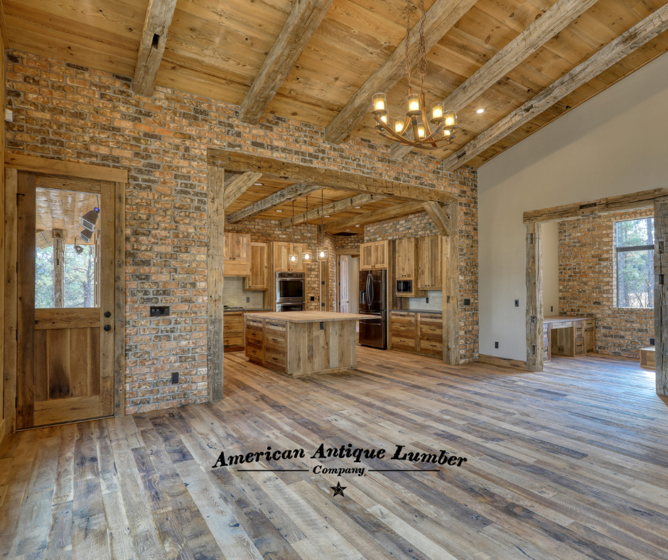 Brick wall with reclaimed wood door on the left and entry into a kitchen with a center wood island. 