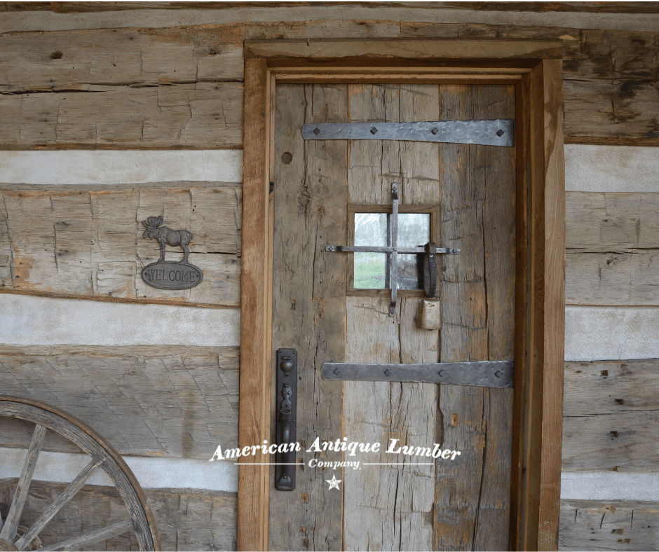 Reclaimed hand hewn siding with chink joint and hand hewn door with ornate metal work and metal cross over middle window.