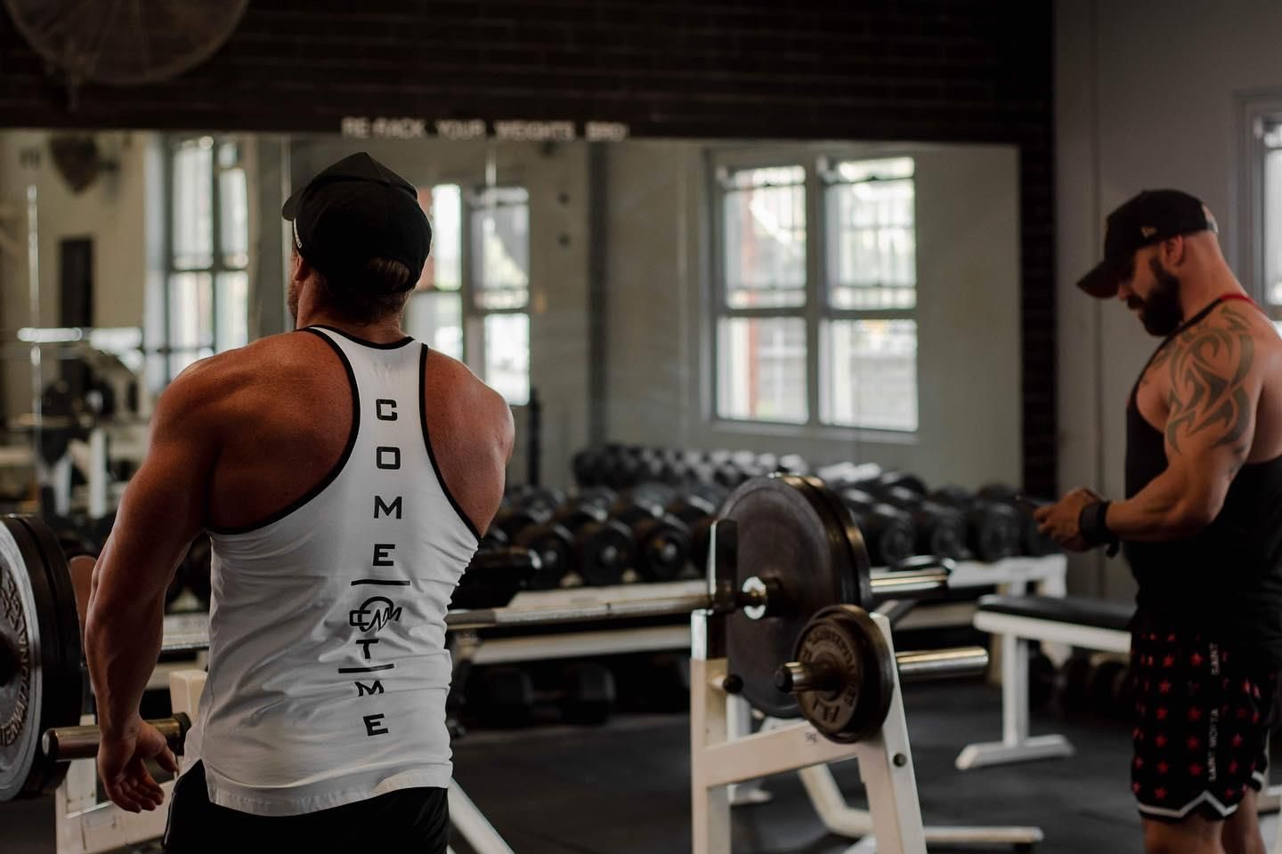 Two Men Are Standing in a Gym With Dumbbells and a Barbell — The Factory Gym in Taree, NSW