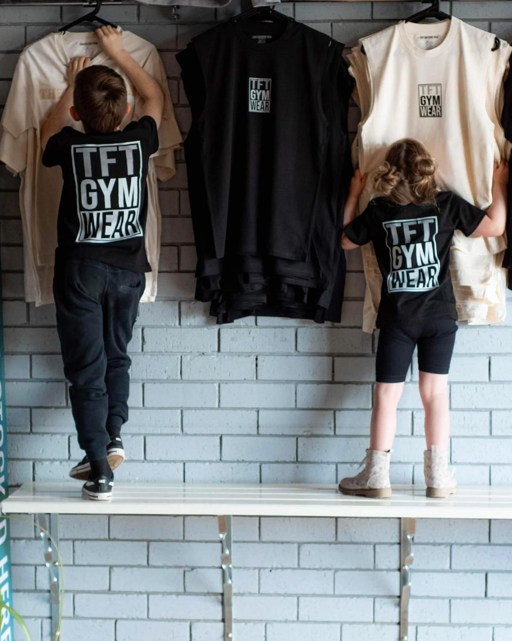 A Boy and a Girl Are Looking at TFT Gym Wear Shirts — The Factory Gym in Taree, NSW
