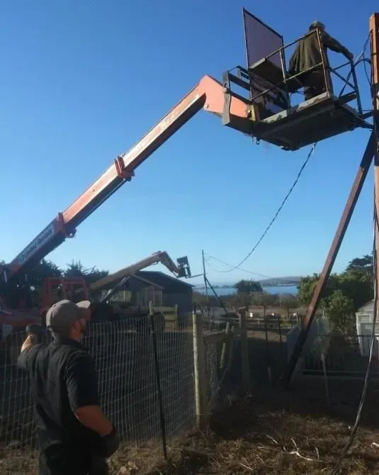 A man is standing in front of a crane that says ' jlg ' on it