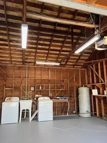 A laundry room with a washer and dryer , sink , and water tank.