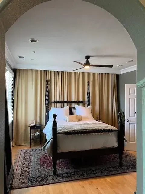 A bedroom with a four poster bed and a ceiling fan