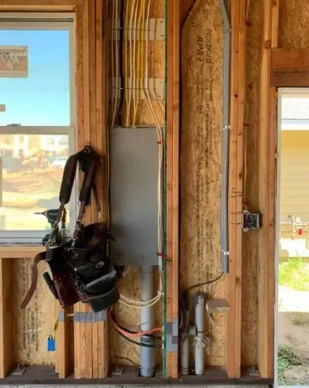 A wall with a lot of wires hanging from it and a window.