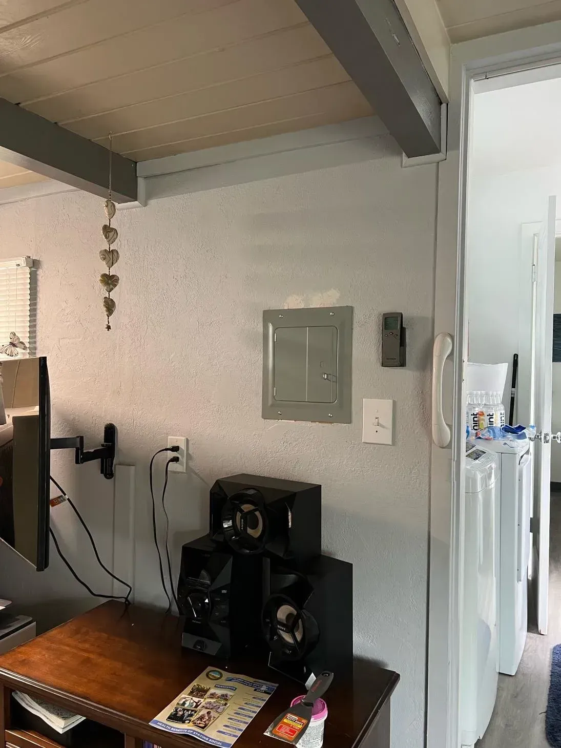 A living room with a television , speakers , and a desk.