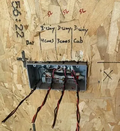 A box with wires coming out of it on a wooden wall
