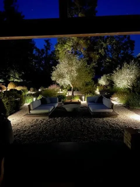 A patio area with a lot of furniture and trees at night.
