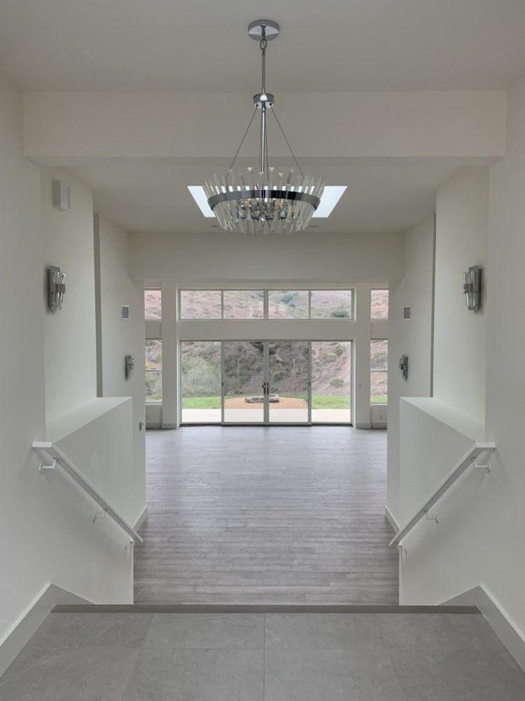 An empty hallway with stairs and a chandelier hanging from the ceiling