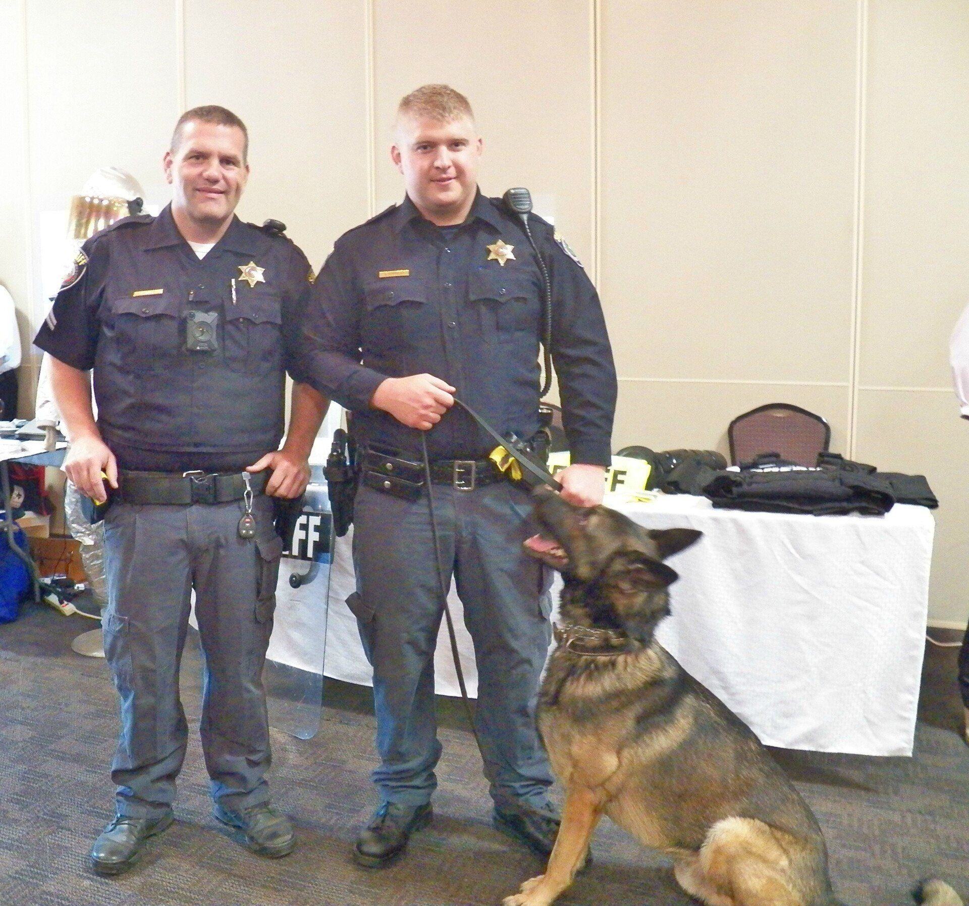 Two police officers standing next to a german shepherd