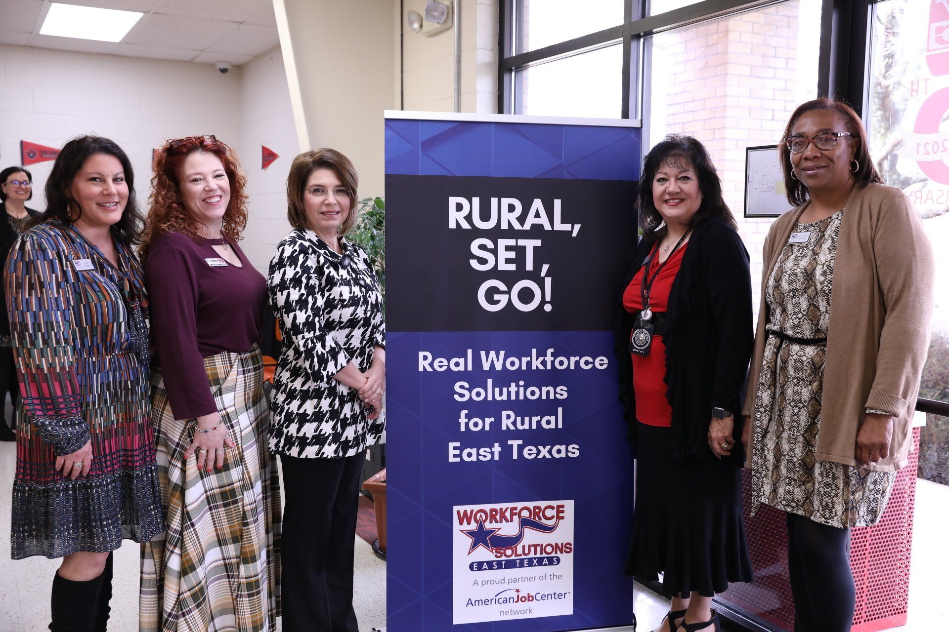 A group of women standing next to a sign that says rural set go