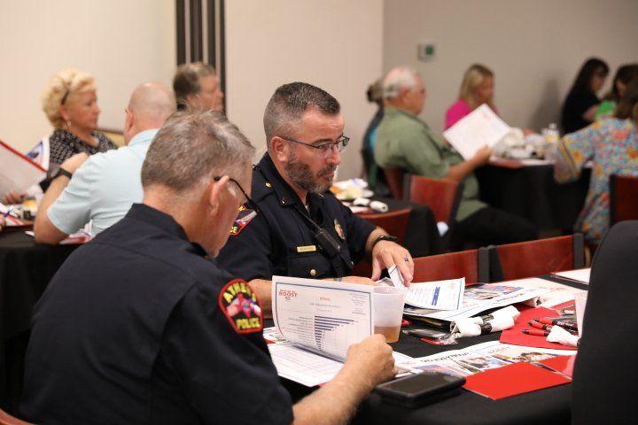 Two police officers are sitting at a table looking at papers.