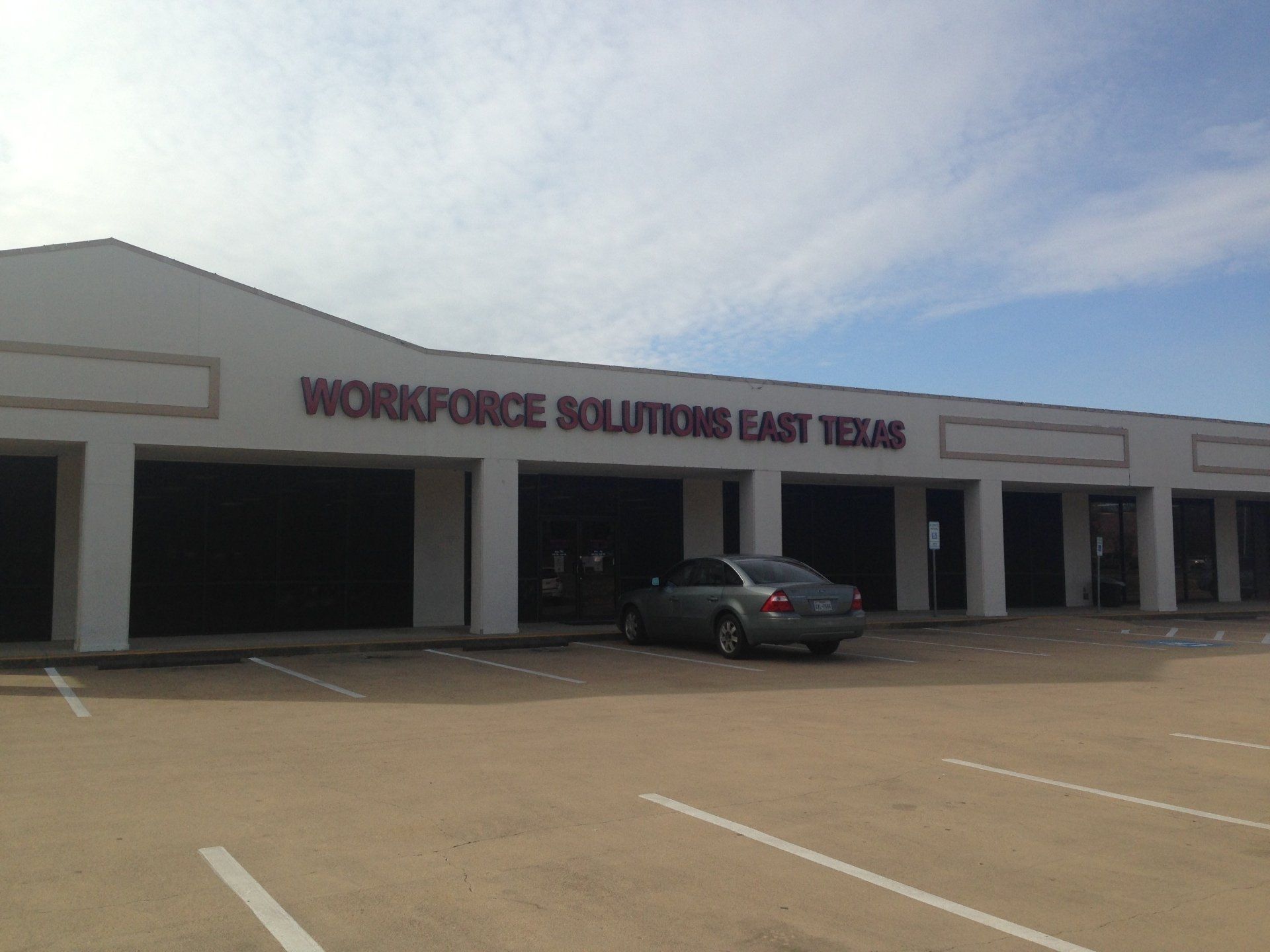 A car is parked in front of a building that says workforce solutions east texas
