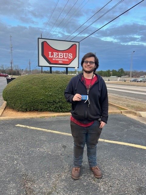 Man holding giftcard in front of company sign
