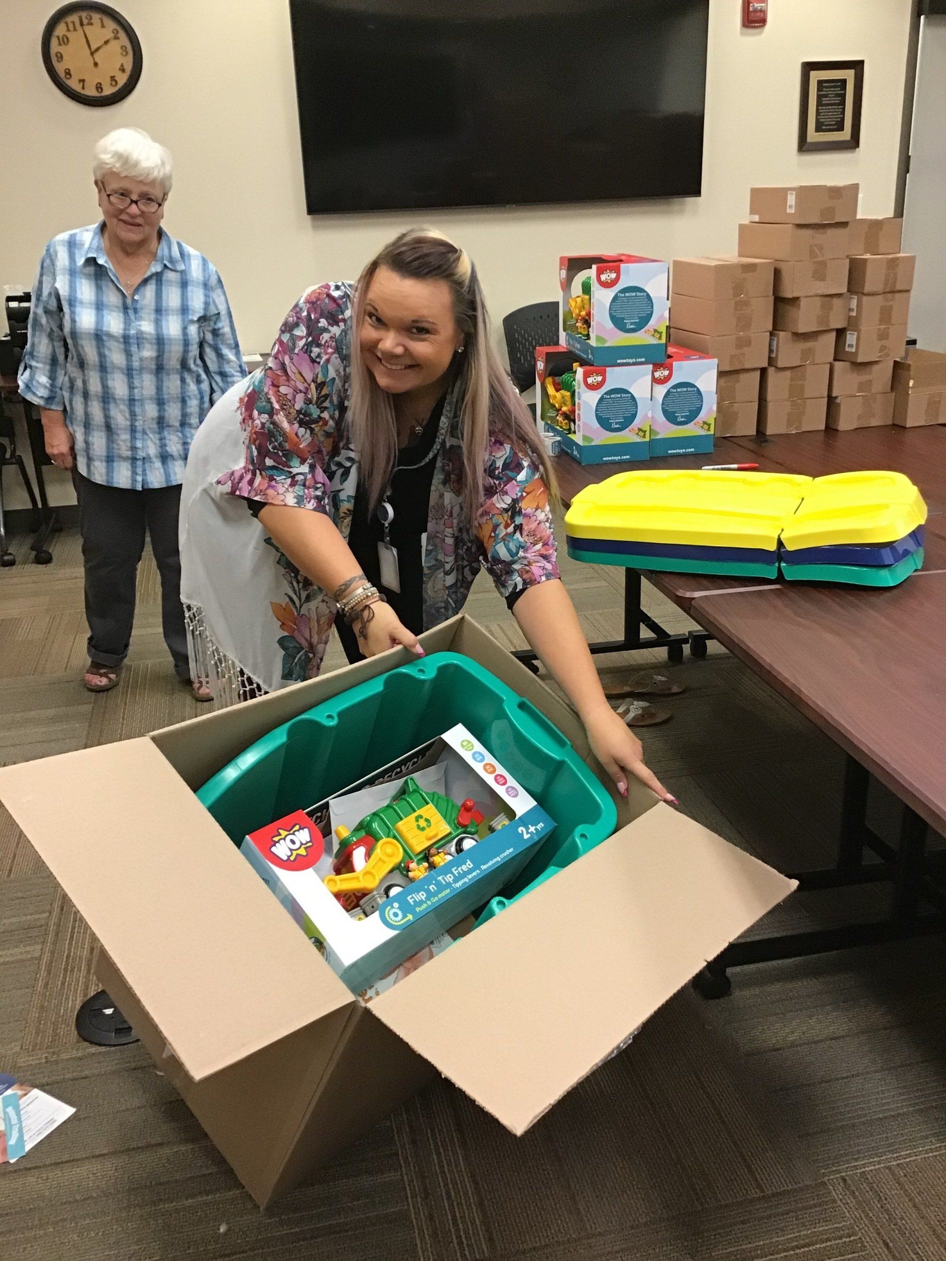 A woman is opening a box with toys in it