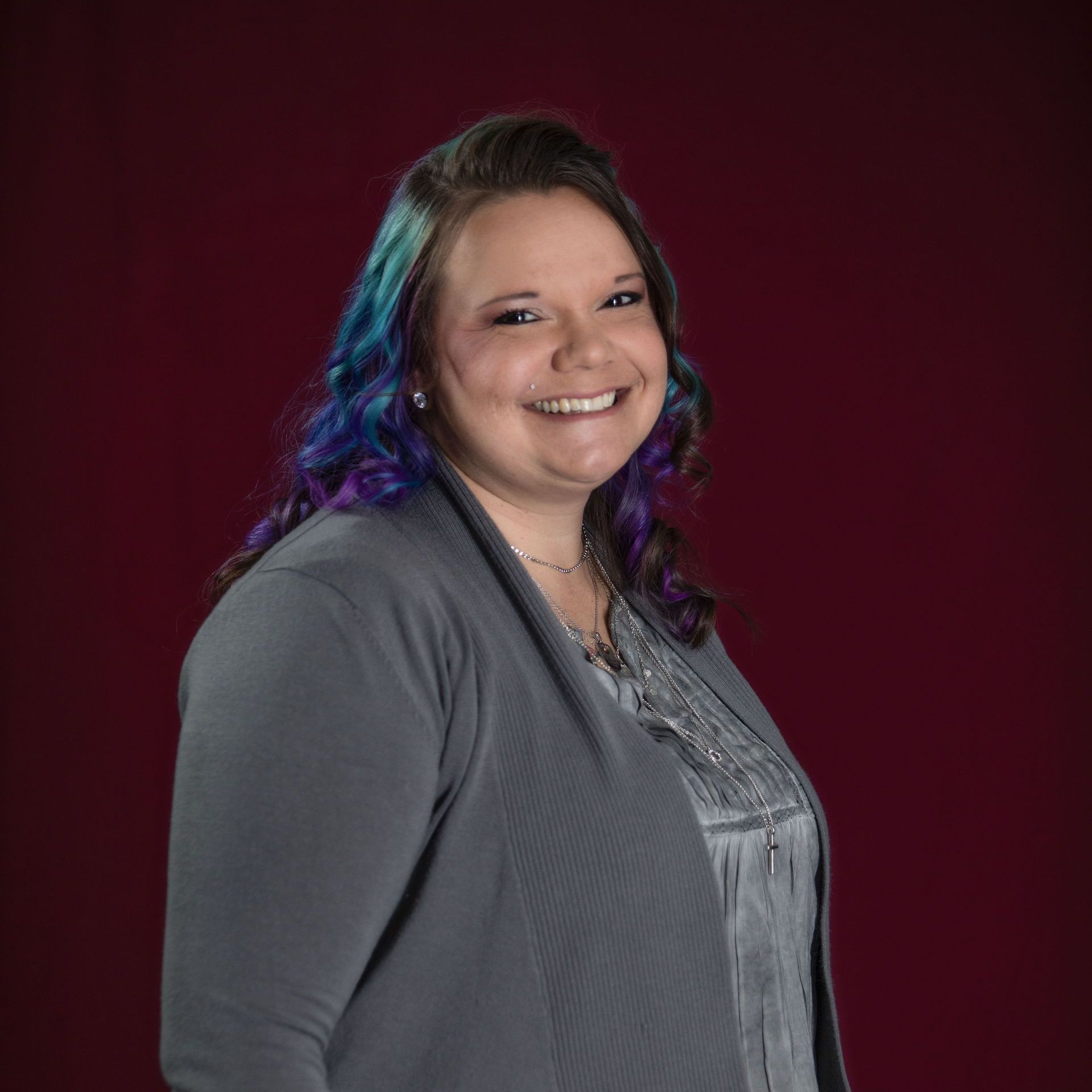 A woman with blue and purple hair is smiling for the camera.