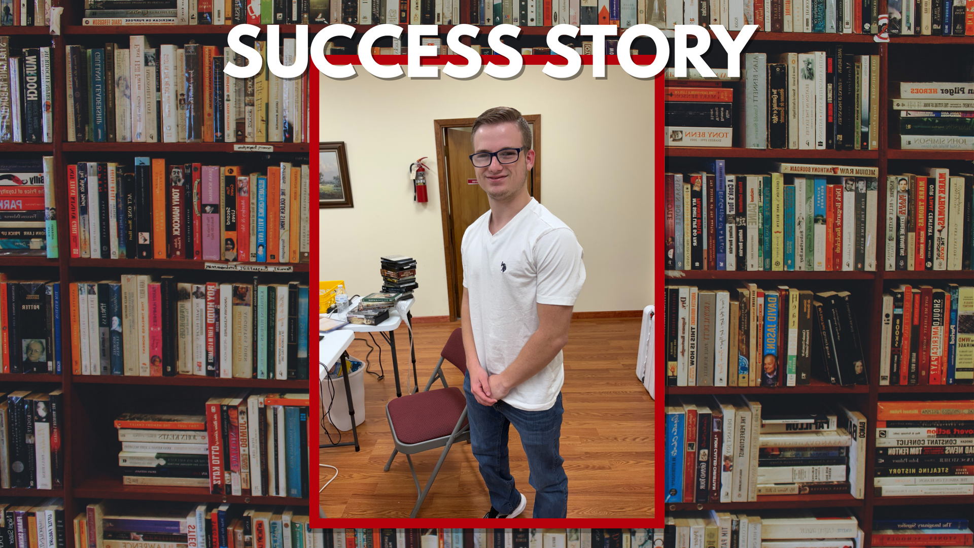 A man in a white shirt stands in front of a bookshelf. The words 