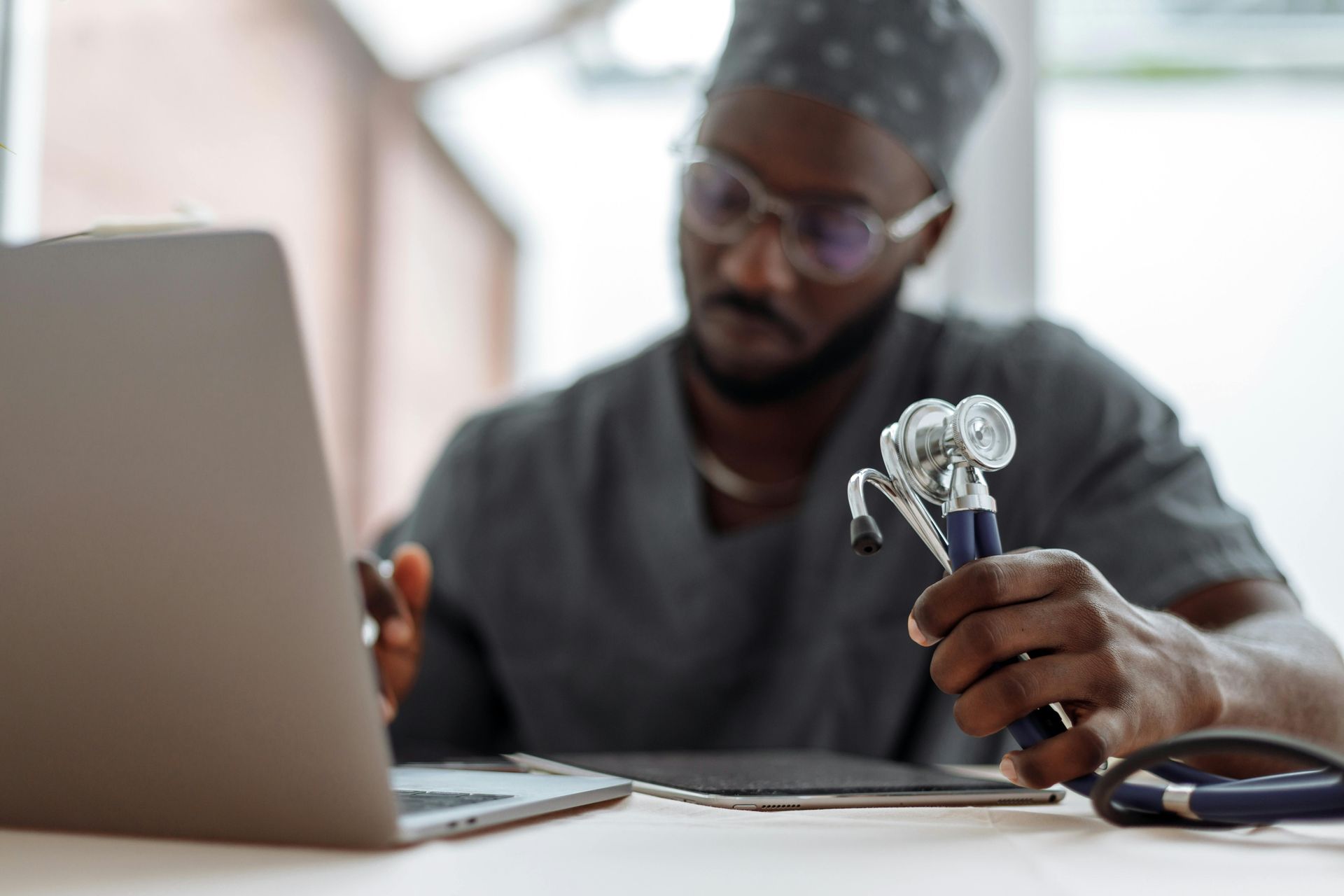 A doctor is holding a stethoscope in front of a laptop computer.