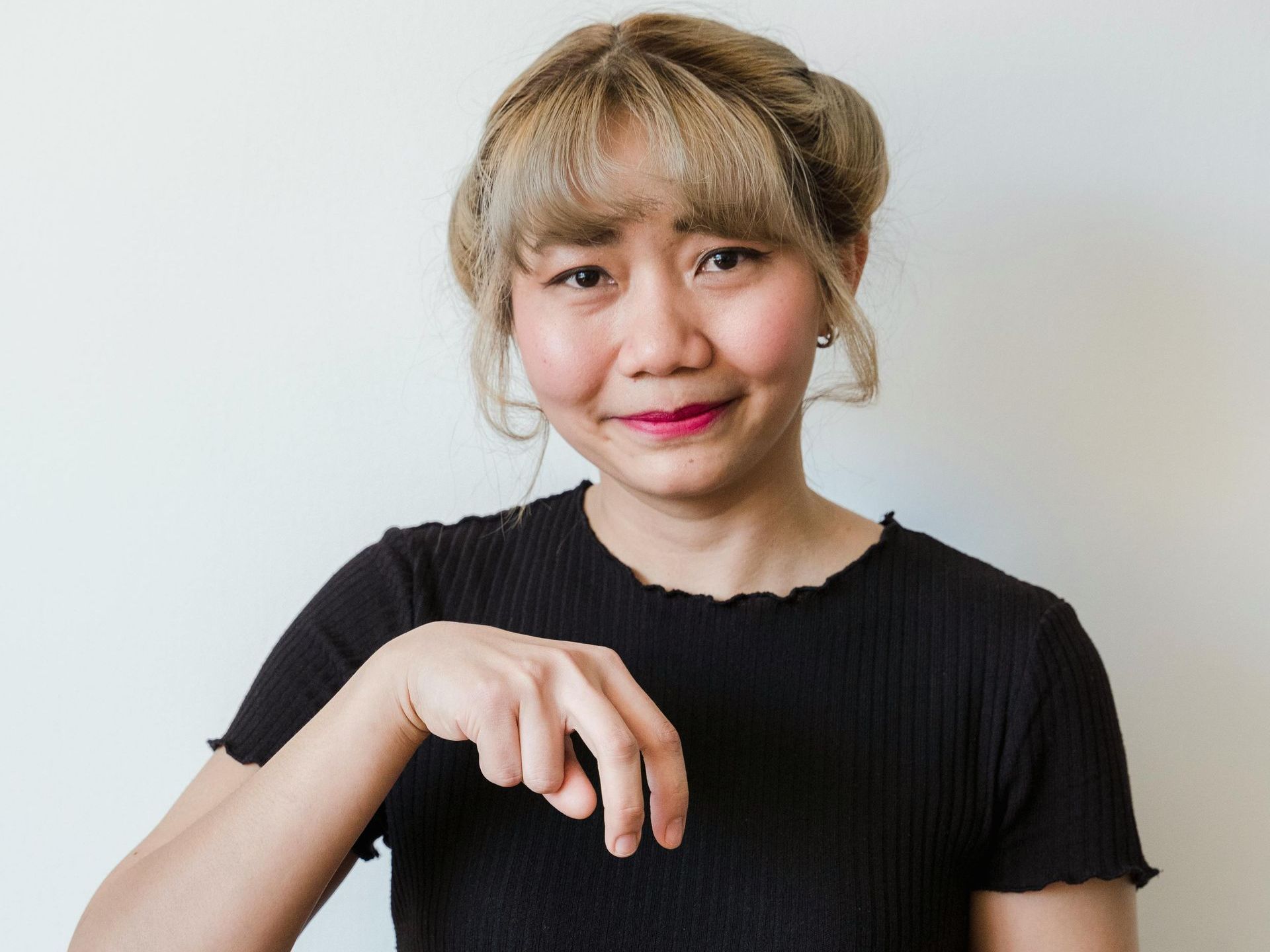 A woman in a black shirt is making a gesture with her hand.