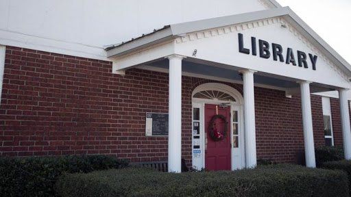 The front of a library with a red door and a wreath on it.