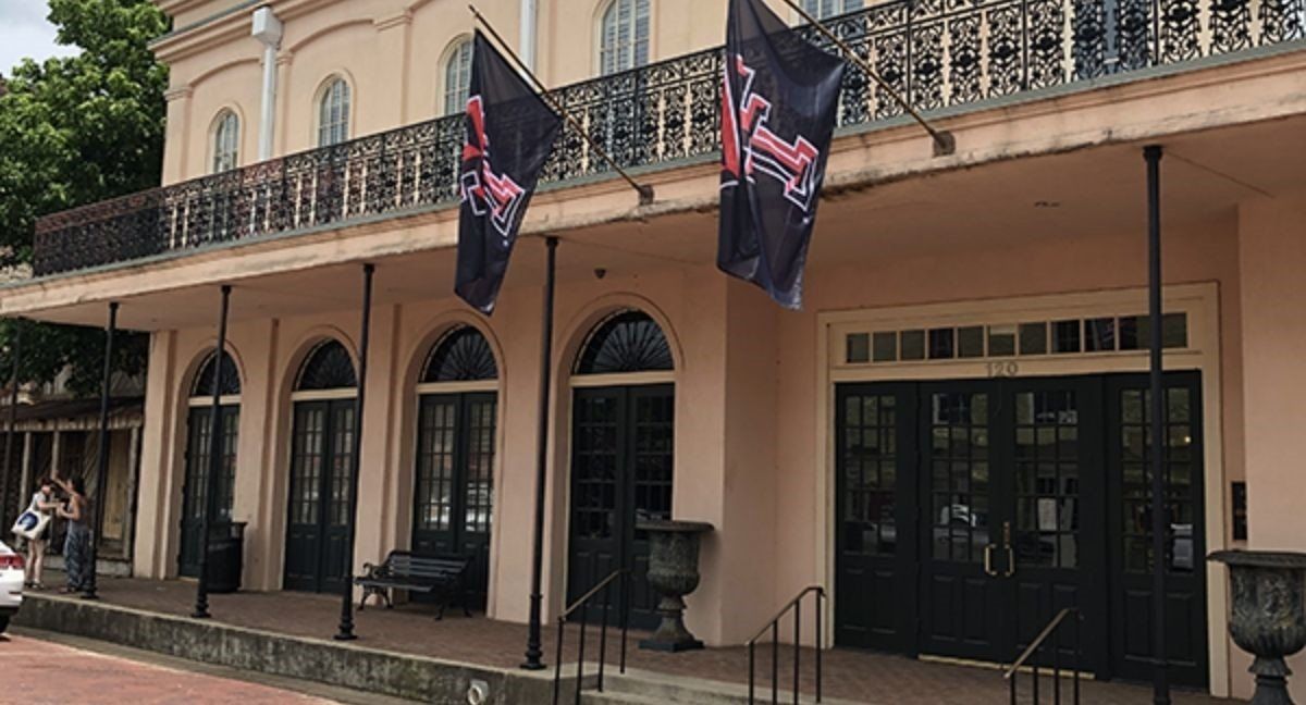 A large building with a balcony and flags hanging from it.