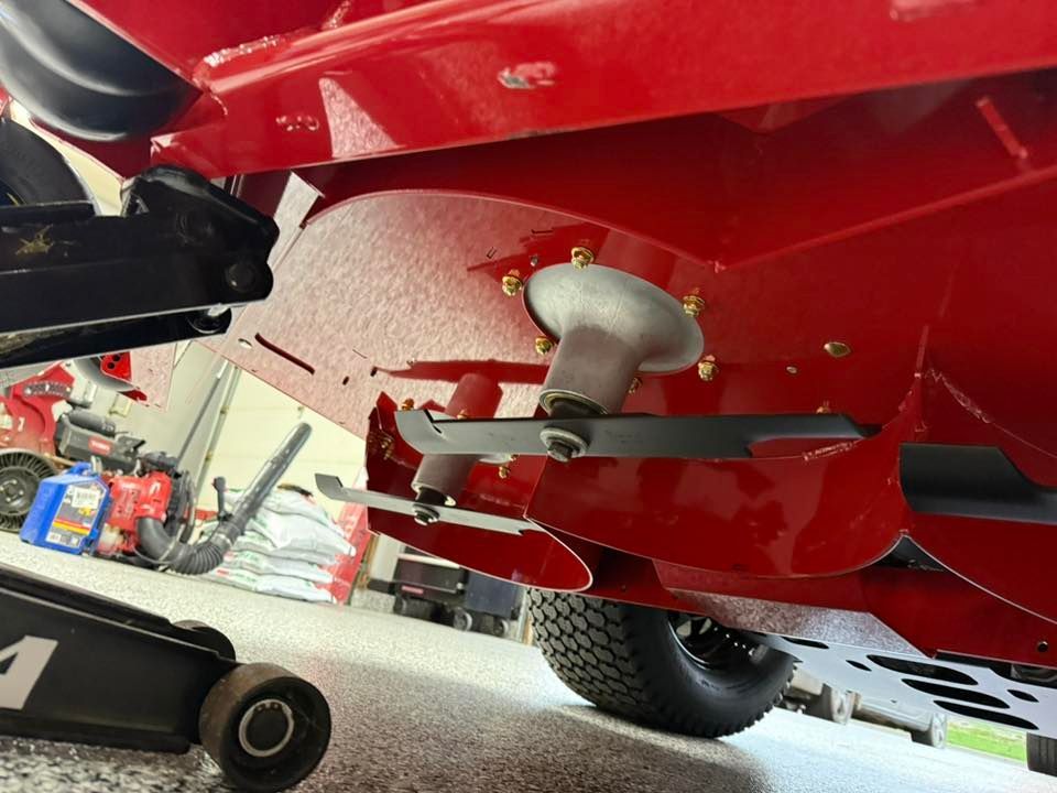 A red lawn mower is sitting on a jack in a garage.