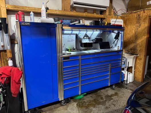 A blue toolbox is sitting in a garage next to a car.