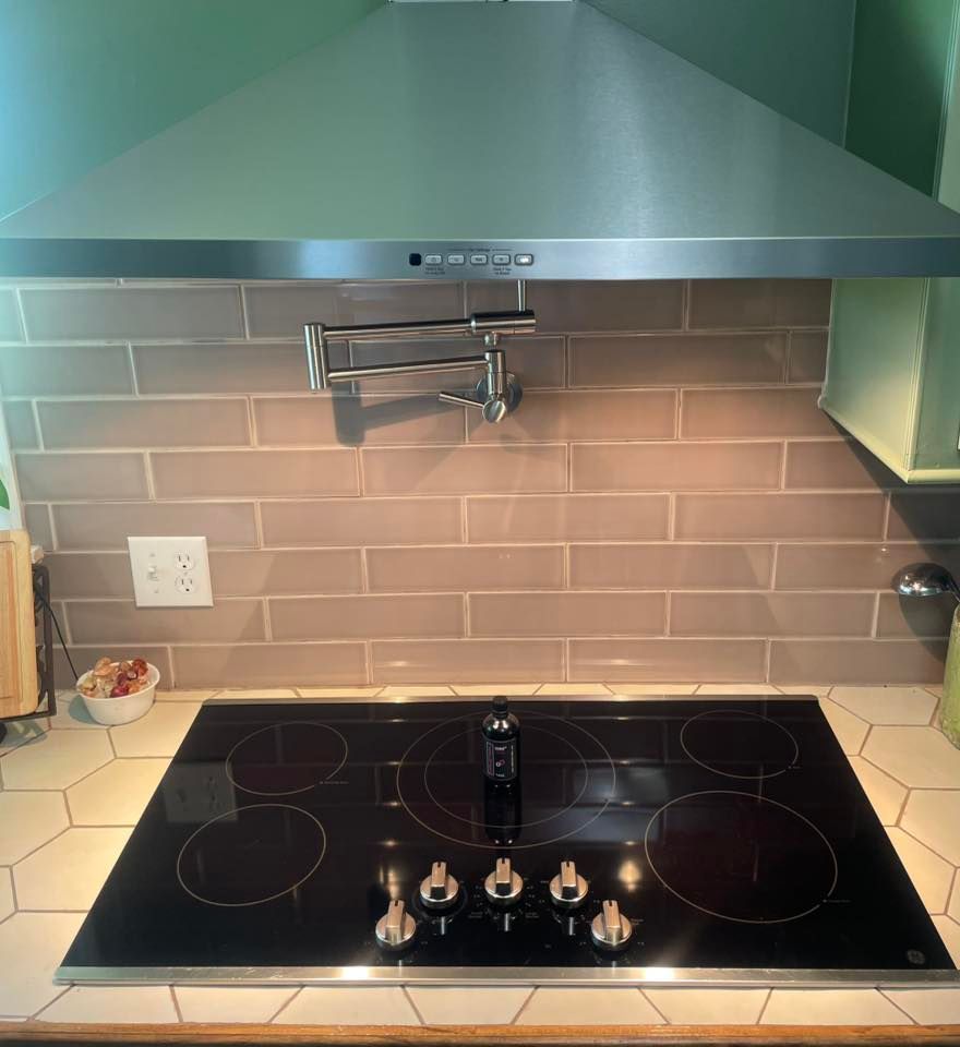 A kitchen with a stove top oven and a stainless steel hood.