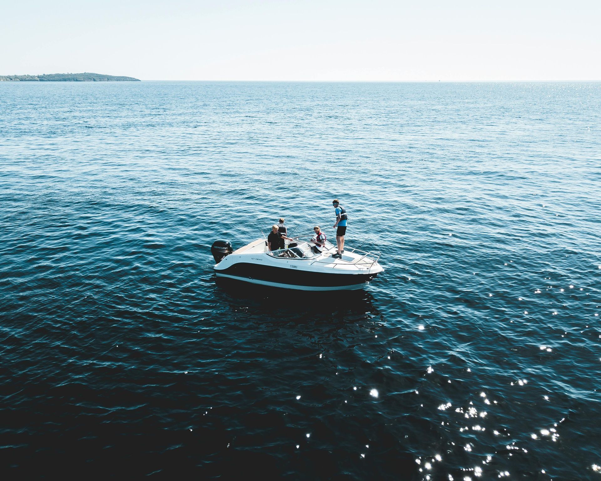 A group of people are riding on the back of a boat in the ocean.