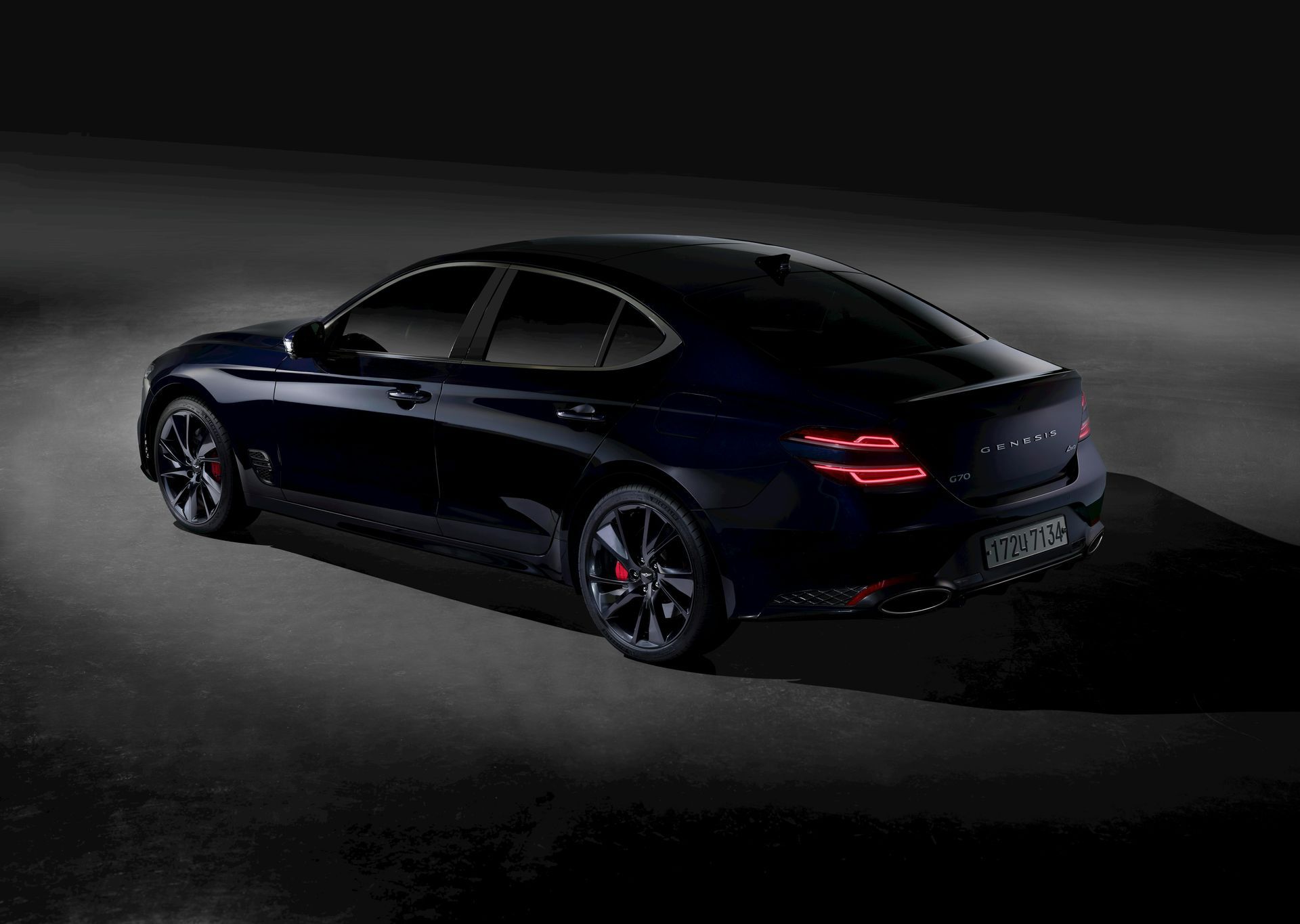 A black car is parked on the side of the road in the dark.