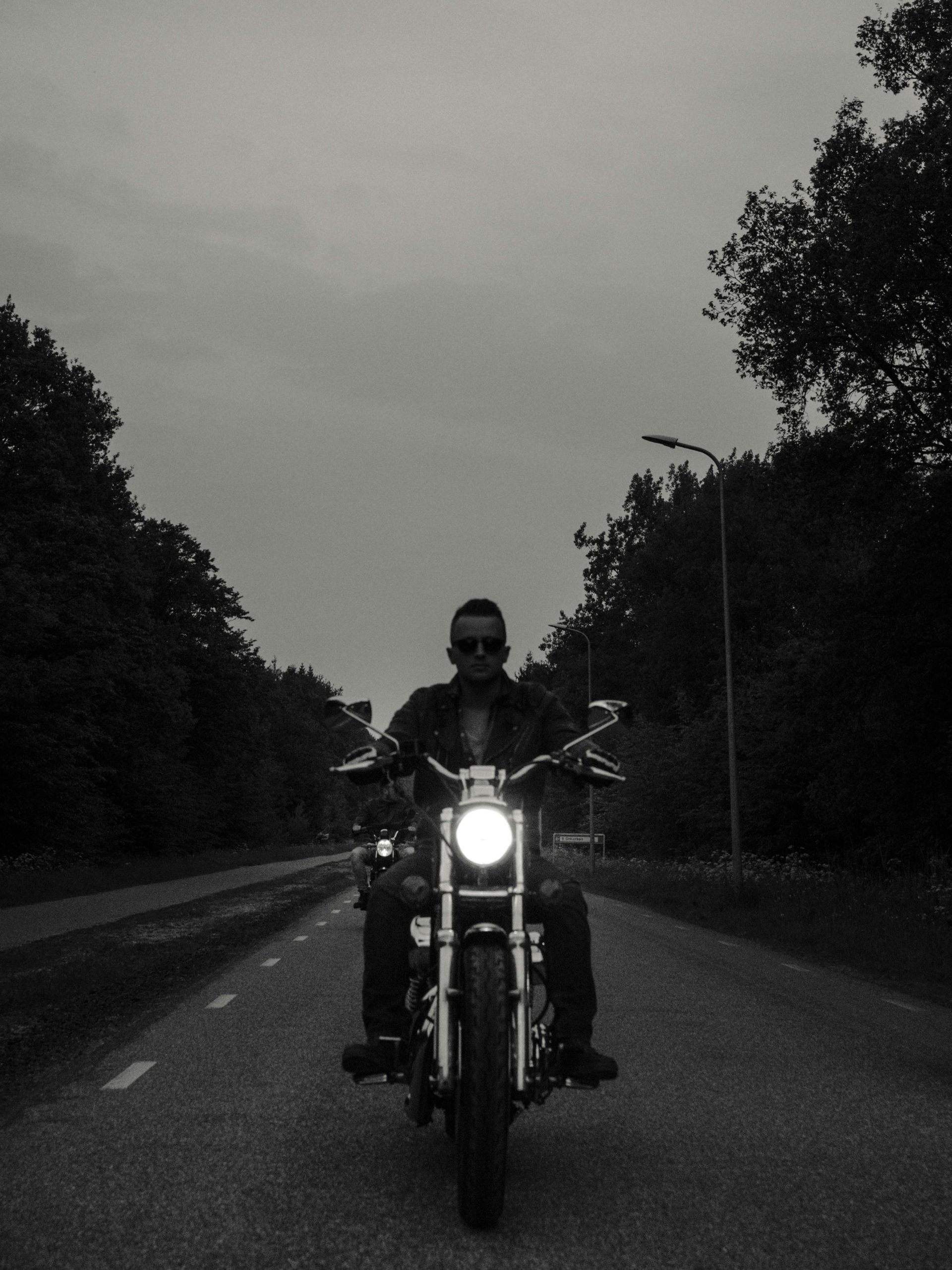 A man is riding a motorcycle down a road at night