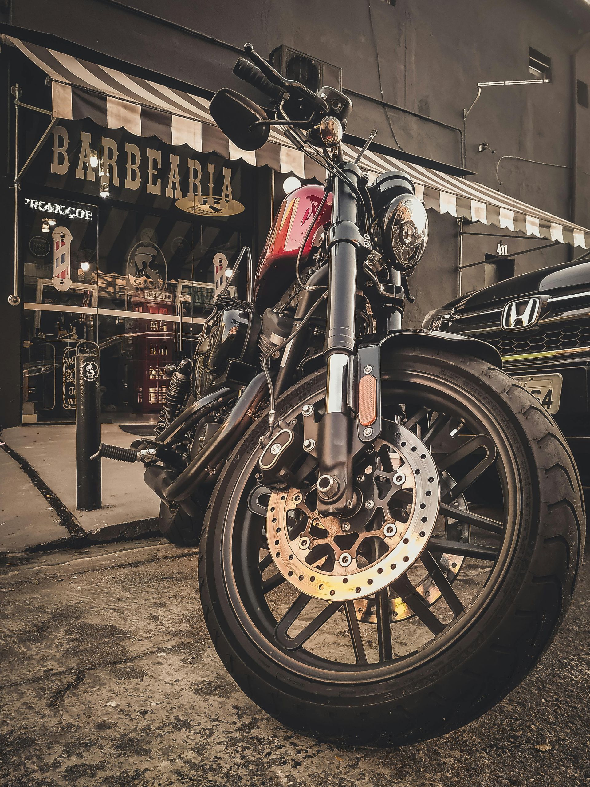 A motorcycle is parked in front of a barber shop.