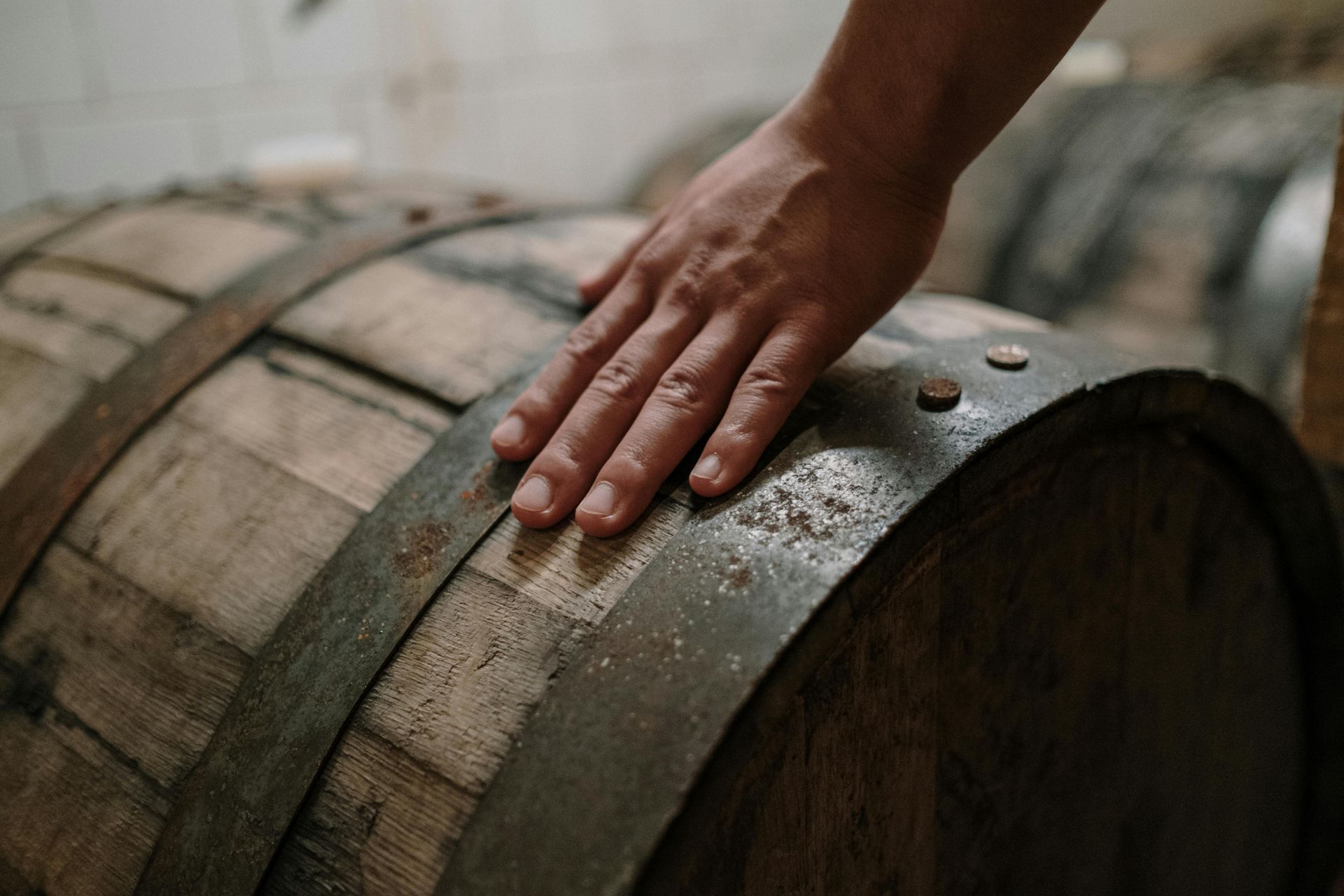 A close up of a person 's hand on a wooden barrel.