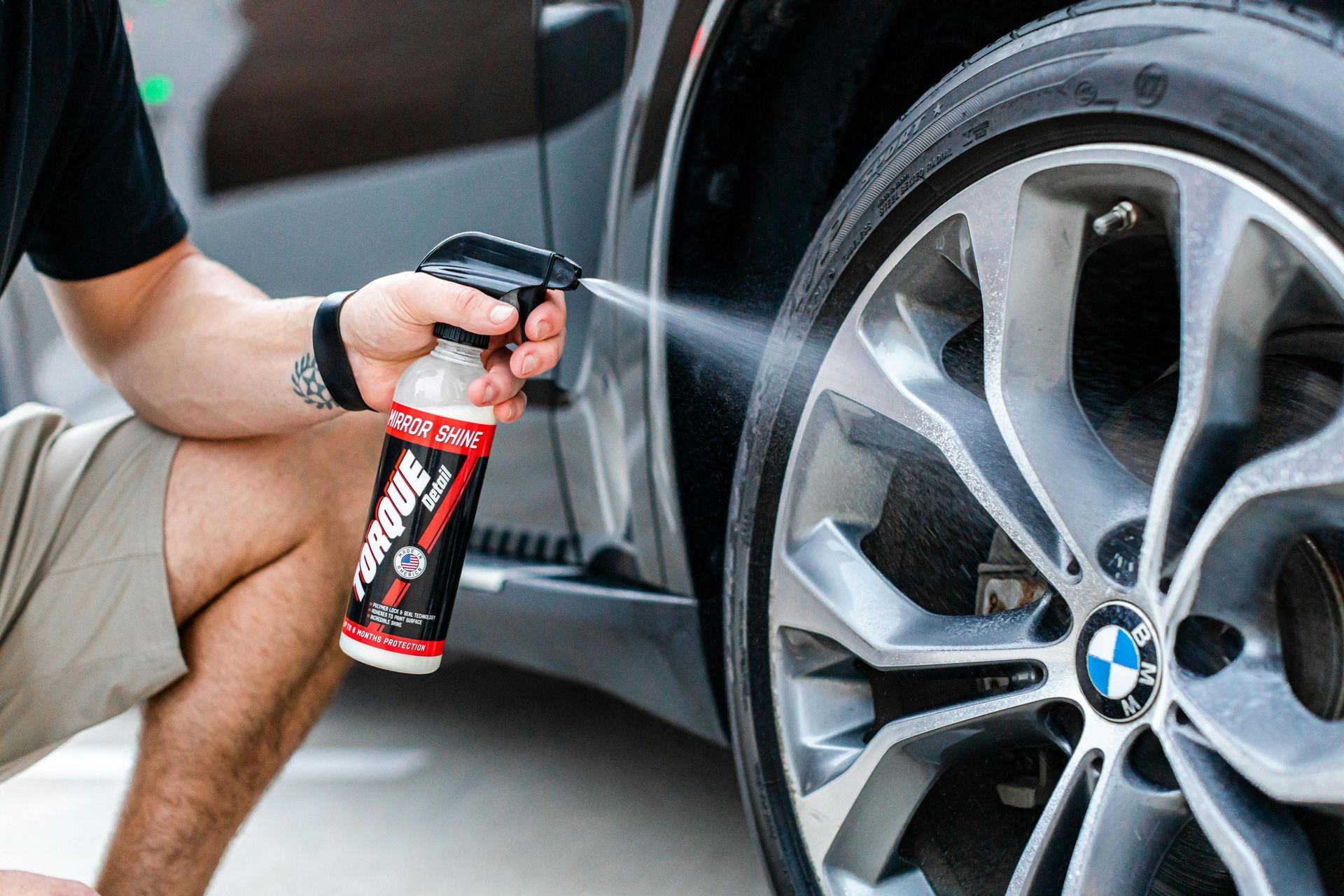 A man is spraying a tire with a spray bottle.