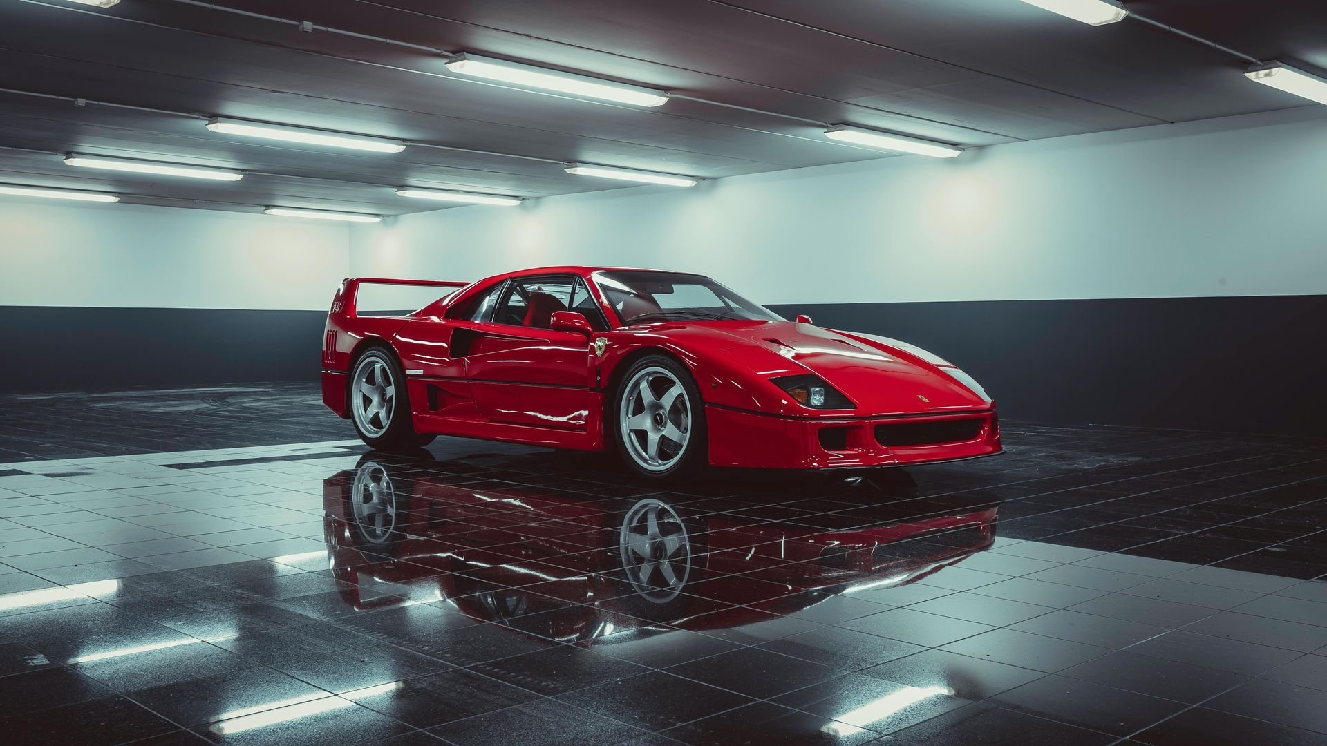 A red ferrari f40 is parked in a garage.