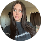 Woman with long brown hair in a dark gray tie-dye shirt, looking off-camera.