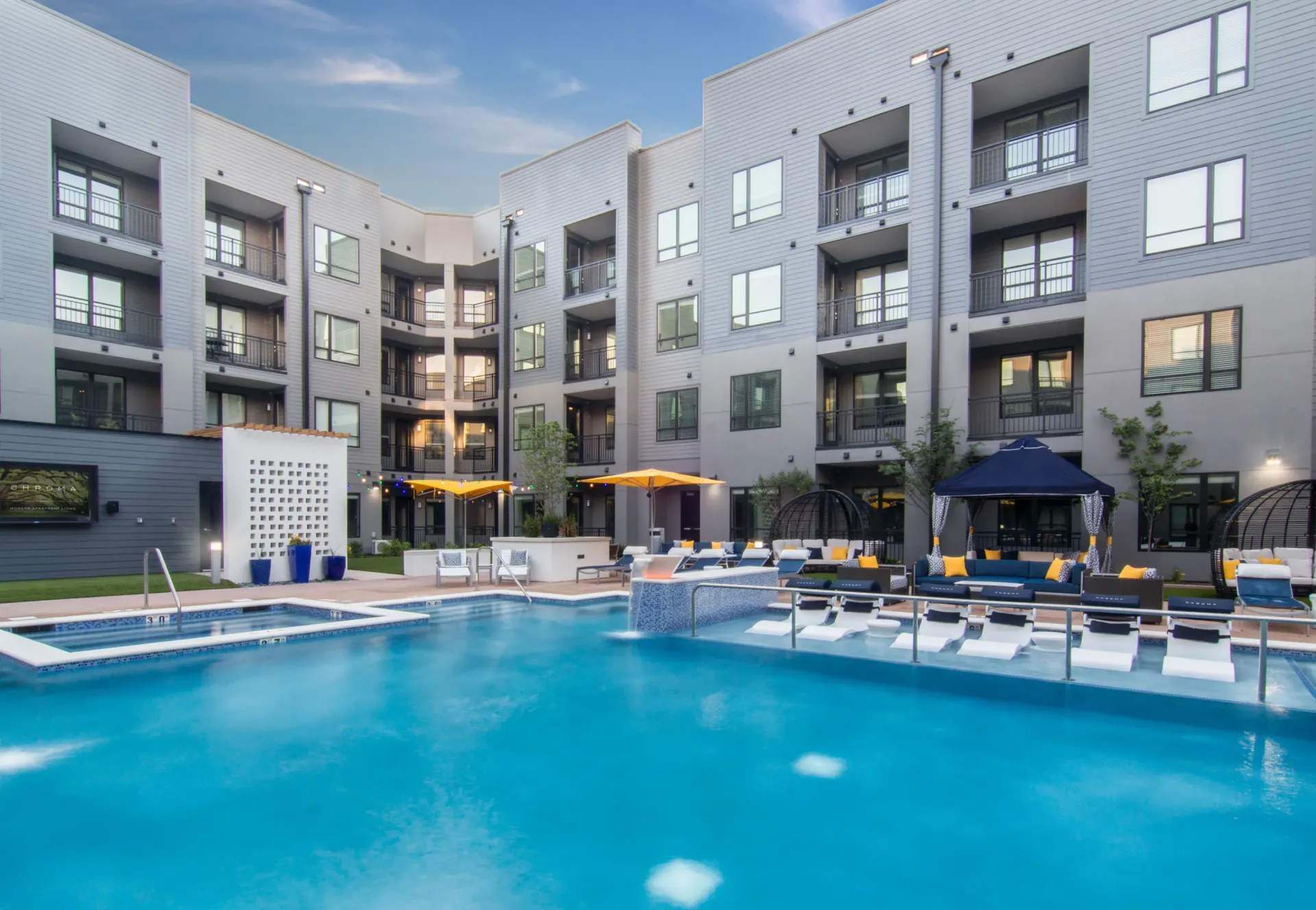 Pool area with lounge seating and modern apartment buildings surrounding a courtyard.