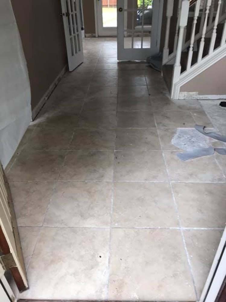A hallway with tile floors and stairs in a house.