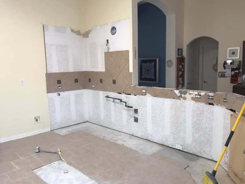 A kitchen that is being remodeled with a broom on the floor