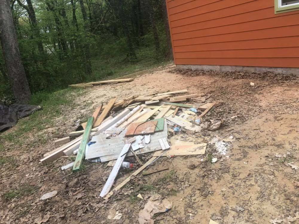 A pile of wood is sitting in the dirt in front of a house.